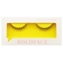 The Short and Sweet false eyelashes by Boldface are presented in a white rectangular box featuring a clear display window. The cruelty-free lashes are highlighted against a vibrant yellow backdrop. The packaging is adorned with