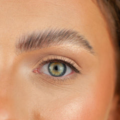 A close-up of a face emphasizes a green eye accentuated by Boldface's Short and Sweet lashes and a perfectly groomed eyebrow. The skin displays a smooth texture with a natural complexion, embodying the essence of cruelty-free beauty.