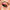 Close-up of an eye with striking makeup: featuring shimmery gold and deep copper eyeshadow, thick black eyeliner, and the voluminous Ardell Faux Mink Lashes in Black Demi Wispies. The eyebrow is meticulously groomed. The makeup artist's handle