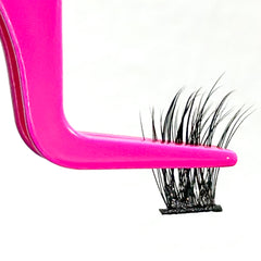 Close-up of a pink eyelash applicator holding a segment of Pinky Goat Pre-Glued Under Lashes - Scarlett against a plain white background. The black eyelash extensions feature a cluster of fine, pointed lashes that fan out at the tips, creating a wispy finish. These reusable lashes from Pinky Goat ensure effortless beauty.