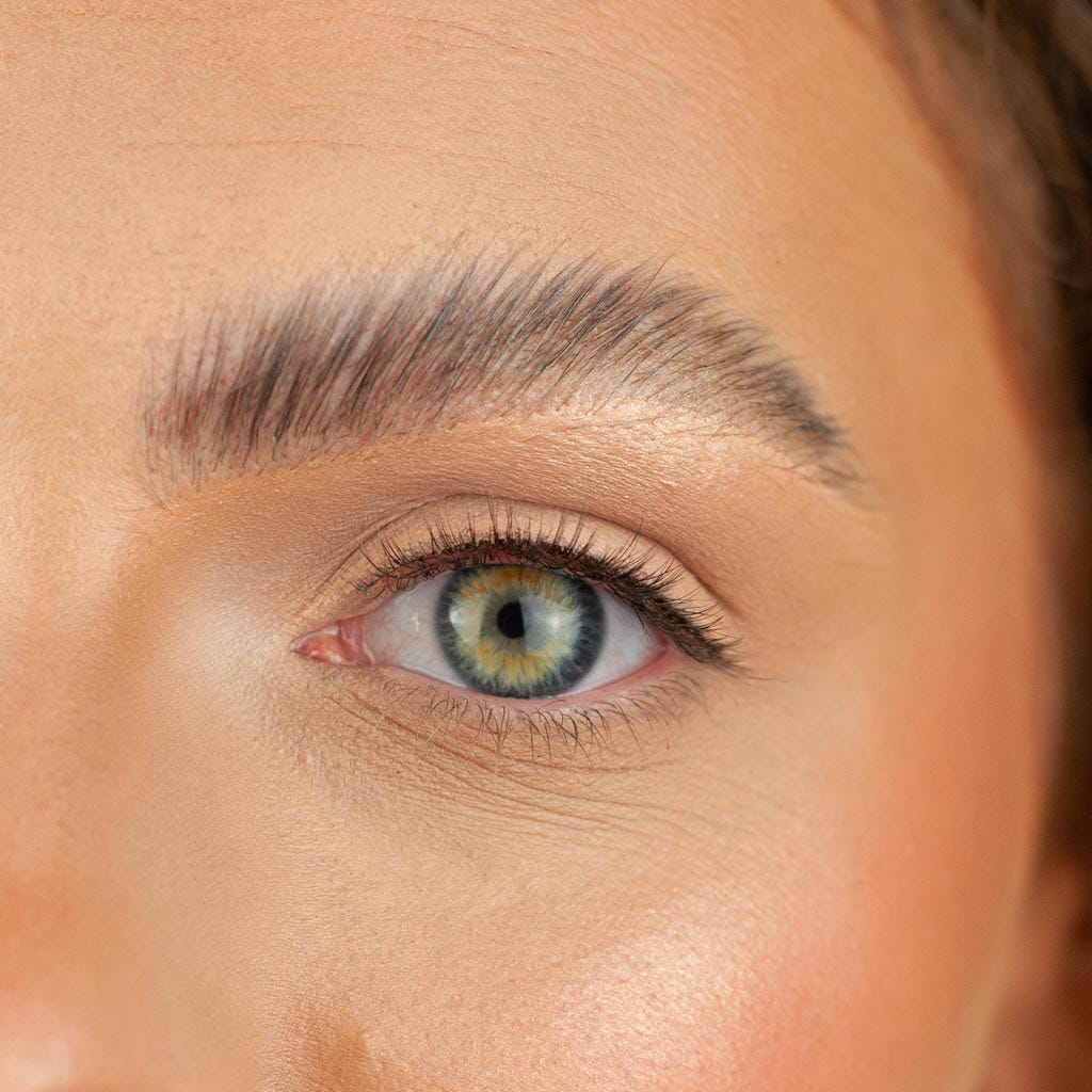 A close-up of a face emphasizes a green eye accentuated by Boldface's Short and Sweet lashes and a perfectly groomed eyebrow. The skin displays a smooth texture with a natural complexion, embodying the essence of cruelty-free beauty.