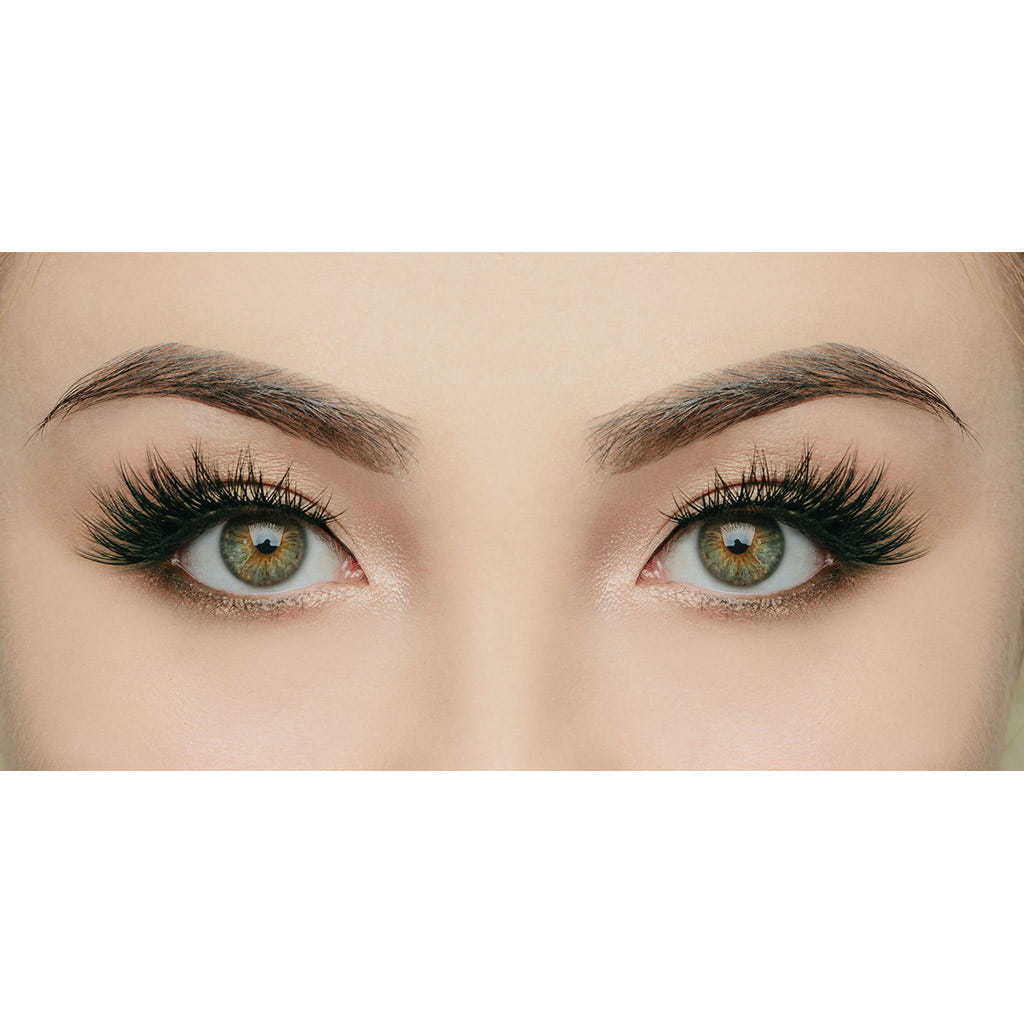 Close-up view of a pair of beautifully made-up eyes with striking green and brown irises. The eyes feature long, voluminous eyelashes and well-defined eyebrows, framed by skilfully applied eye makeup enhanced by House of Lashes - Iconic cruelty-free eyelashes.