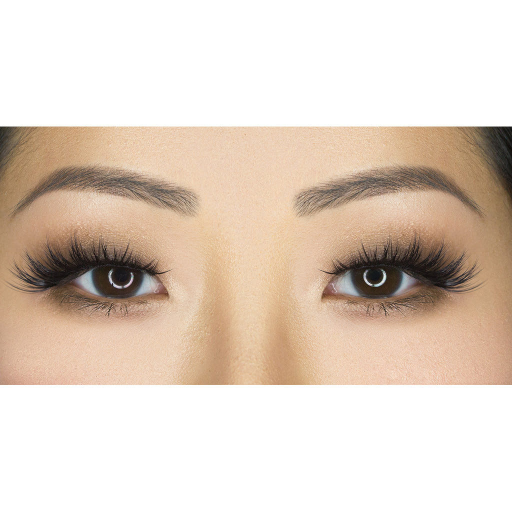 Close-up of a woman's eyes showcasing dramatic makeup. The eyes feature long, voluminous House of Lashes - Iconic eyelashes from House of Lashes and bold eyeliner. Her well-groomed and defined eyebrows enhance the striking look against a white background. Additionally, these cruelty-free lashes make an ethical style statement.