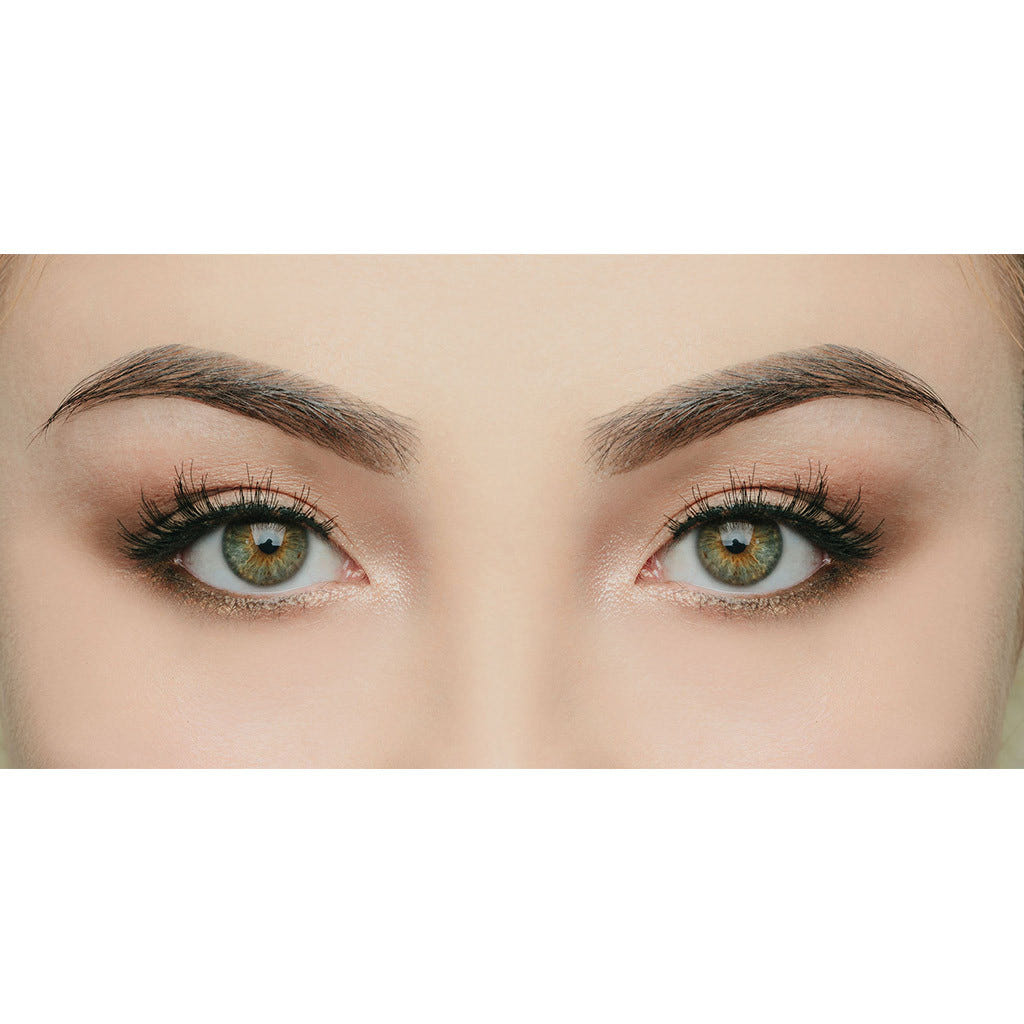 Close-up of a person's eyes and eyebrows. The eyes are green with intricate eye makeup, featuring brown eyeshadow, eyeliner, and mascara that enhances the dramatic eyelashes. The eyebrows are neatly shaped and filled in with makeup for a defined look; the lashes could be straight out of House of Lashes - Siren by House of Lashes.